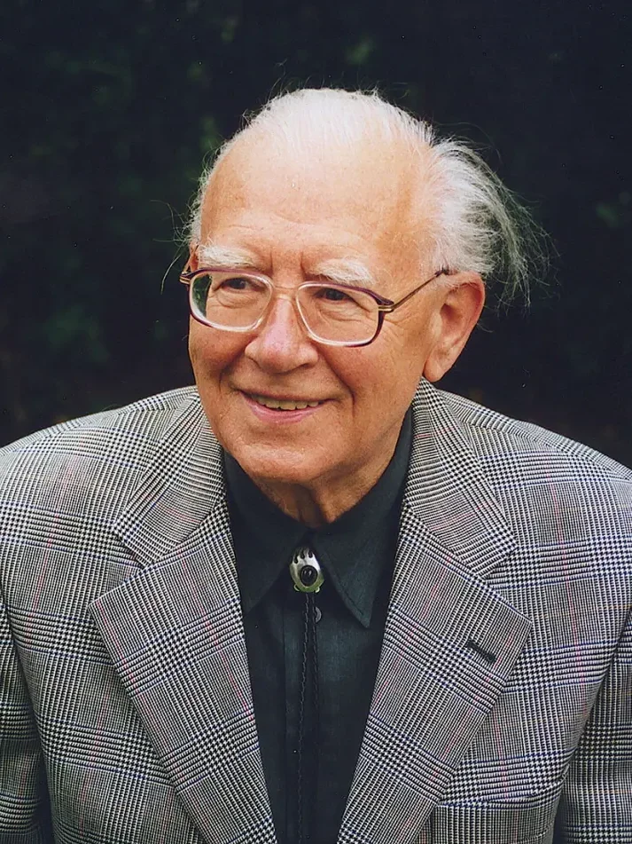 Portrait photograph: Bertold Hummel, smiling, wearing glasses and a bolo tie, outdoors, 2000.