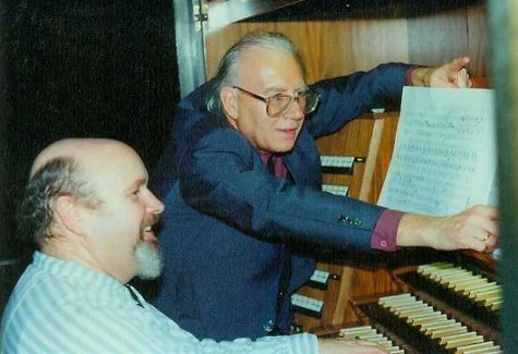Photo en couleur de deux hommes devant une console d'orgue, l'un d'eux désignant une partition d'un bras tendu, lors de la création de l'œuvre op. 91a de Bertold Hummel au Gewandhaus de Leipzig