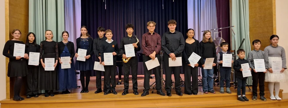 Photo de groupe des lauréates et lauréats du concours d'interprétation 2025 sur scène, avec leurs certificats.