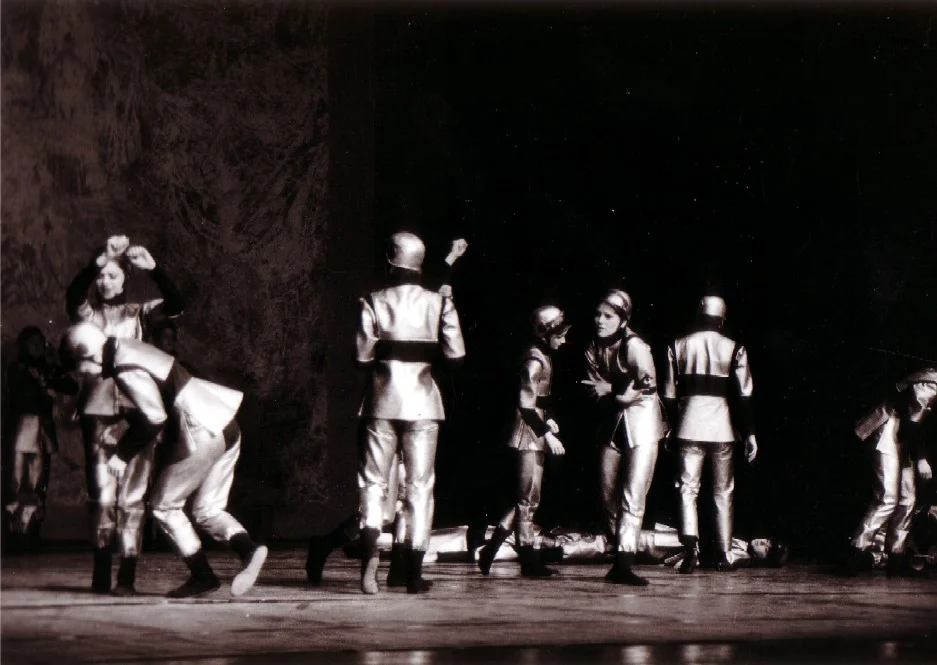 Black-and-white photograph of a ballet scene featuring several dancers in gleaming silver costumes and helmets on a dark stage; still from ‘The Last Flower’ (music: Bertold Hummel, Op. 55a), Würzburg 1975