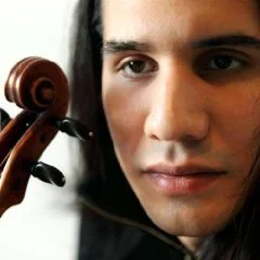Photo portrait d'un violoncelliste en gros plan, avec la volute de son violoncelle au premier plan.