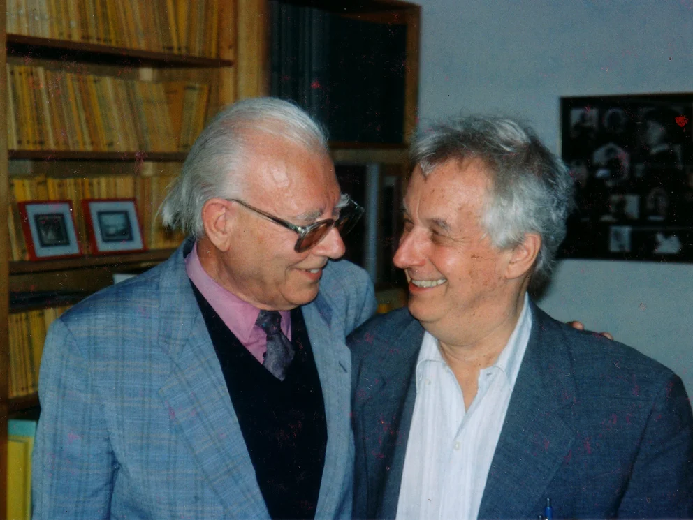 Farbfoto: der Komponist Bertold Hummel und der Komponist Dieter Schnebel lächelnd nebeneinander im Schott-Verlag, Mainz, Anfang 1998