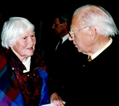 Photo couleur de Bertold Hummel en pleine conversation avec une femme âgée (Elfriede Forbrig), avec une autre personne à l'arrière-plan, prise le 12 novembre 2000 (contexte de la photo : « Six chorals pour saxophone alto »)